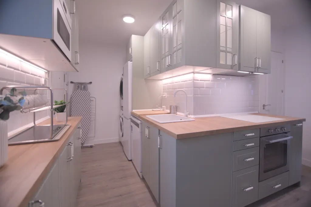 Cocina equipada con encimera de madera, horno y lavadora
